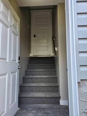 A staircase leading to a door with a textured carpet. - Elegant Family Home by Stadium, Airport, Shopping (Regina)