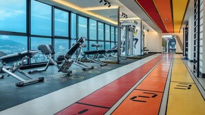 Ein modernes Fitnessstudio mit Trainingsgeräten, großen Fenstern und Blick auf die Stadt.