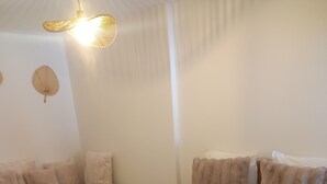 A hotel room with a large bed, a smaller sofa, and two wall-mounted lamps.