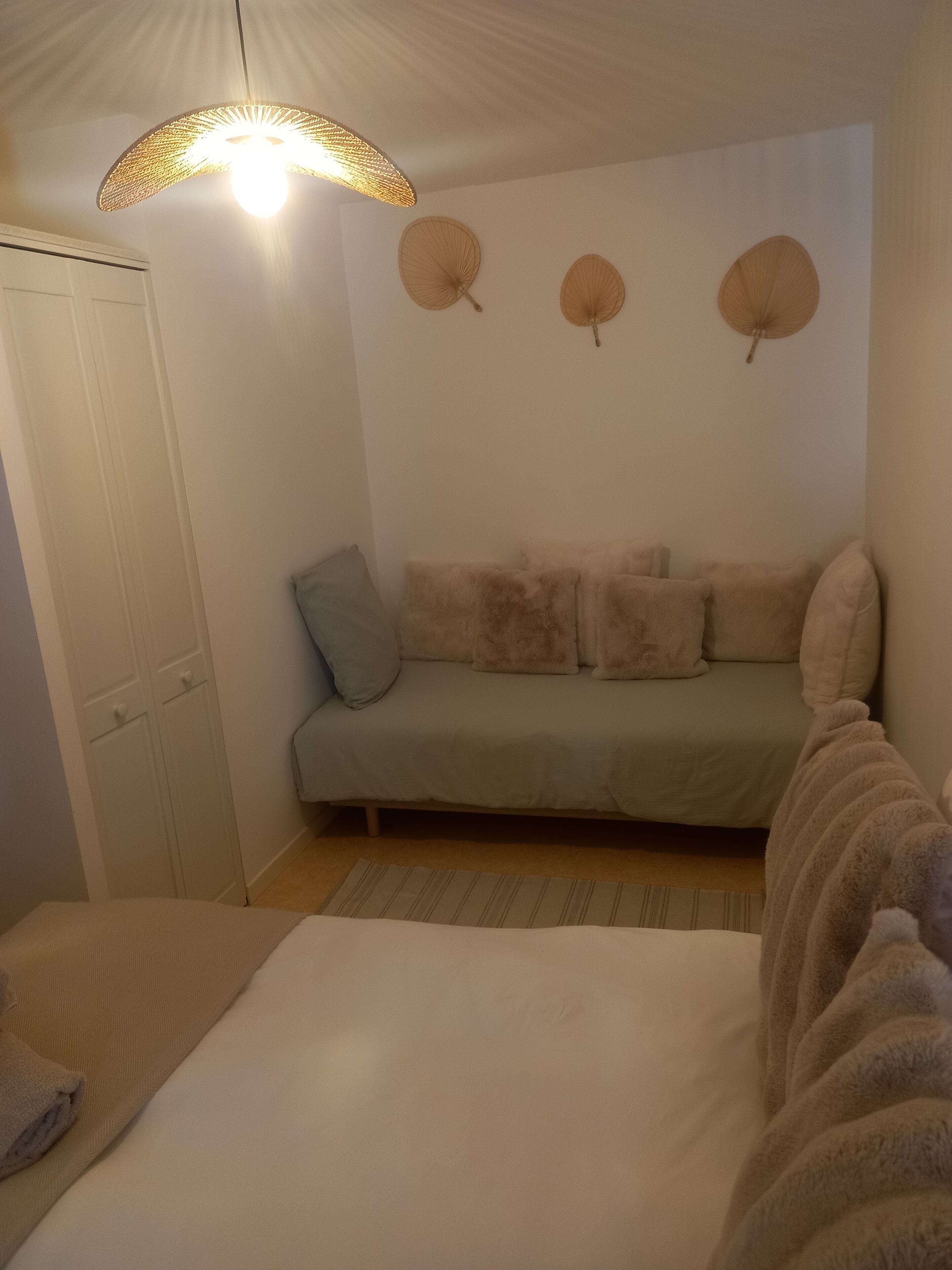 Ett mysigt rum med en säng, en soffa och en hängande lampa.