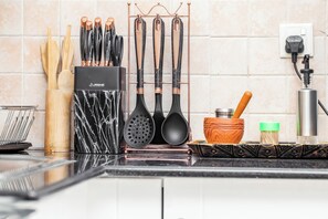 Uma bancada de cozinha com utensílios, um porta-temperos e uma tomada.