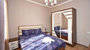 A bedroom with a bed, bedside tables, a mirror, and a chandelier.