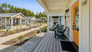 Eine Reihe einstöckiger Häuser mit überdachter Veranda, Sitzgelegenheiten im Freien und einem gepflegten Garten.