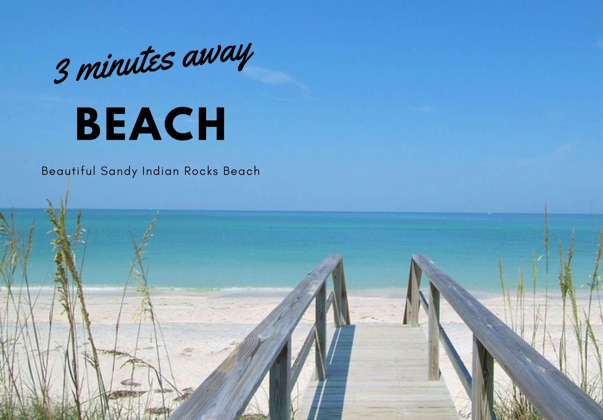 A wooden boardwalk leading to a beach with clear turquoise water and a clear sky.