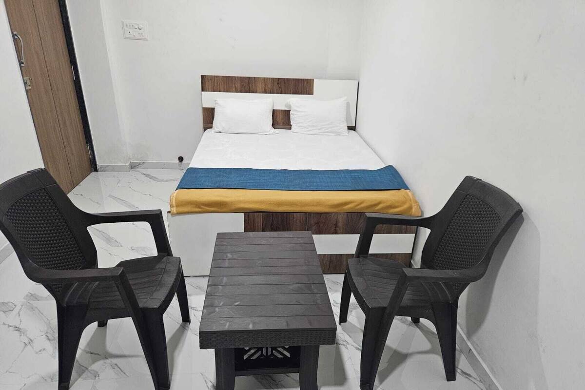 Une petite pièce avec un lit, deux chaises et une table.