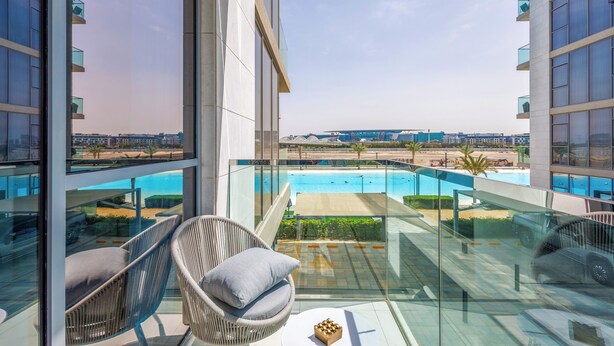 A balcony with wicker chairs and a view of a swimming pool.