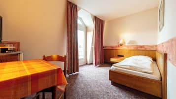 A hotel room with a bed, a desk, a chair, and a table.