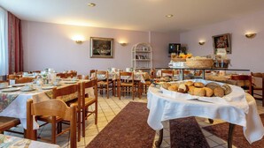 A dining area with multiple tables set for breakfast, featuring bread and pastries. - enjoyHotel garni Korntal Stuttgart  (Korntal-Munchigan)