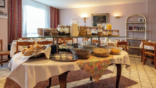 A dining area with a buffet setup, including various food items and serving dishes. - enjoyHotel garni Korntal Stuttgart  (Korntal-Munchigan)