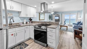 Una cucina moderna con mobili bianchi, piano cottura in acciaio inossidabile e un'ampia finestra con vista sul mare.