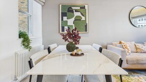 A modern dining area with a marble table, chairs, and a vase with flowers.