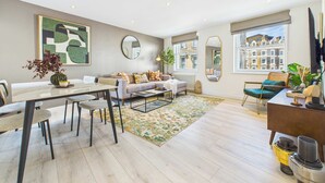 A modern living room with a sofa, coffee table, and a dining area with chairs and a table. - Chic and cosy apartment near Borough Market (Greater London)