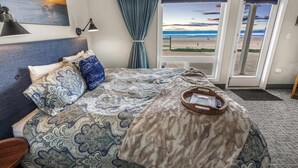 A bedroom with a large bed, a view of the beach, and a curtain. - Ground Floor Studio, Oceanfront Patio, Kitchenette (Lincoln City)