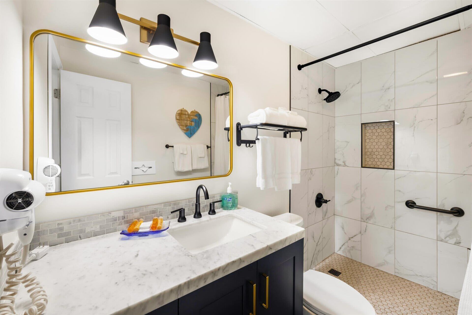 A modern bathroom with a large mirror, a vanity with a sink, and a shower area.