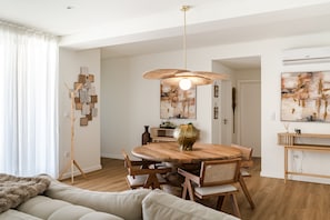 Ein modernes Wohnzimmer mit einem Holzesstisch, einer Couch und einer Pendelleuchte.
