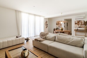 Ein modernes Wohnzimmer mit einer Couch, einem Couchtisch und einem Essbereich im Hintergrund.