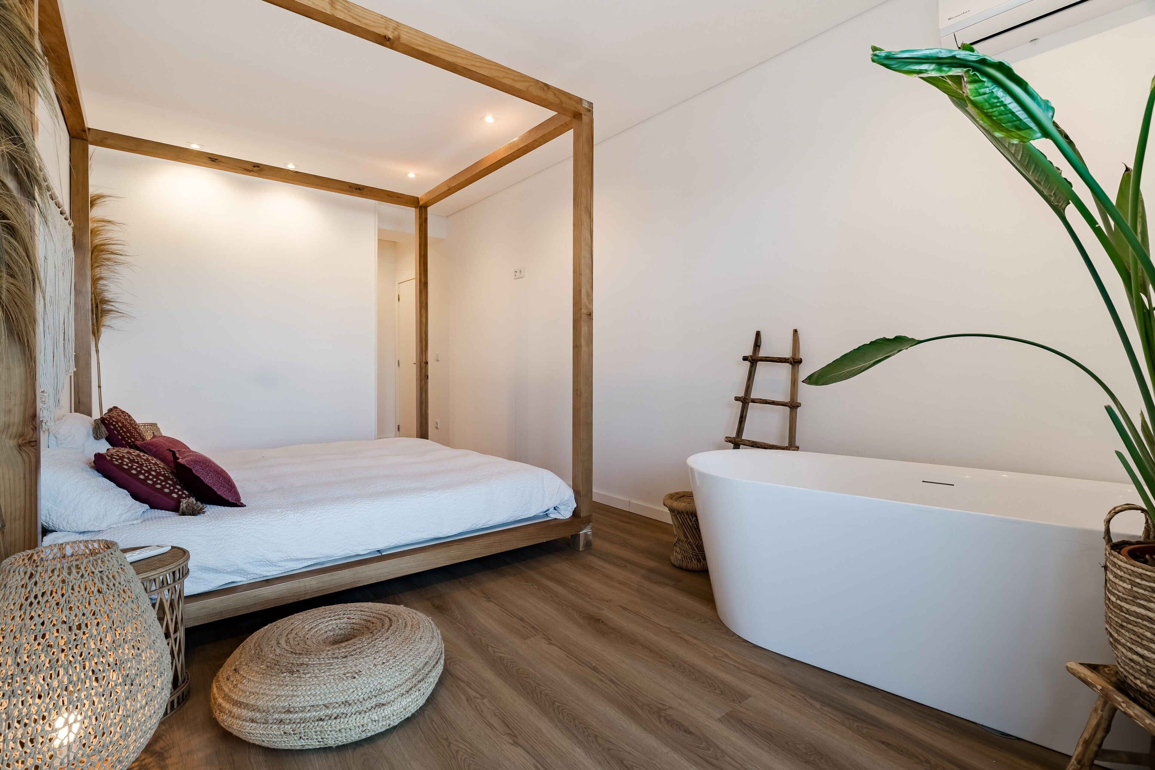 Una habitación con una cama, una bañera y una planta grande.