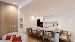 A modern kitchen with white cabinetry, a wooden island, and a dining area with wooden chairs.