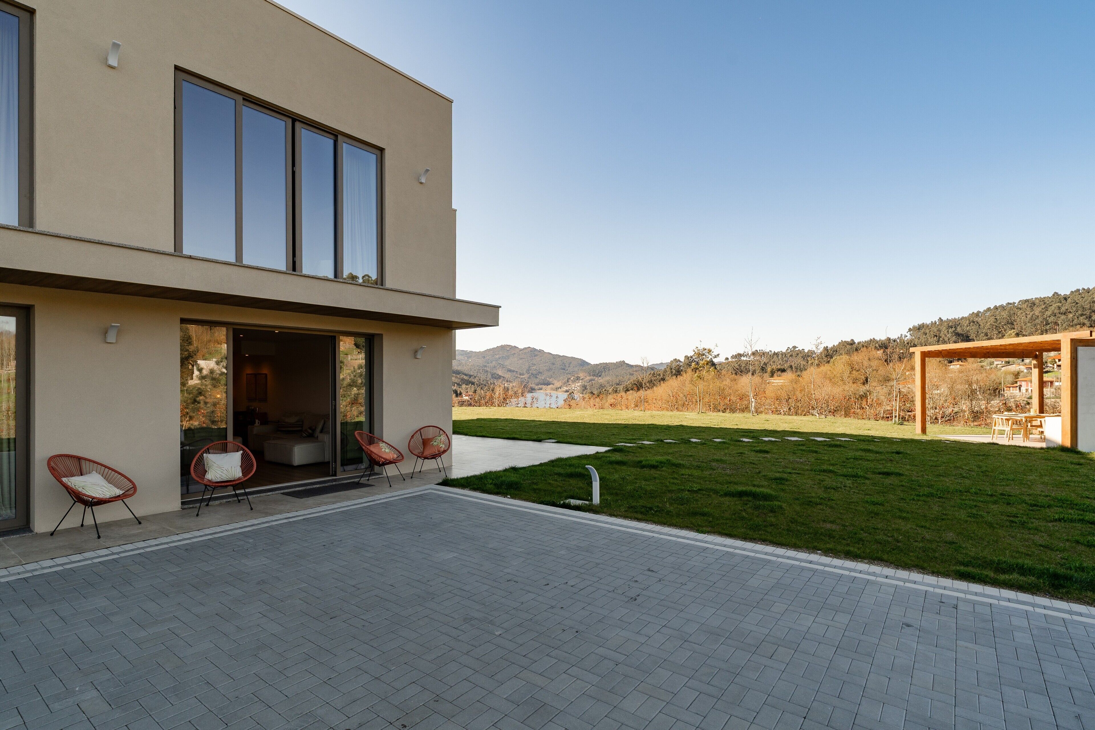 Un bâtiment moderne doté d’un toit plat, de grandes fenêtres et d’un patio dallé avec des espaces pour s’asseoir à l’extérieur.