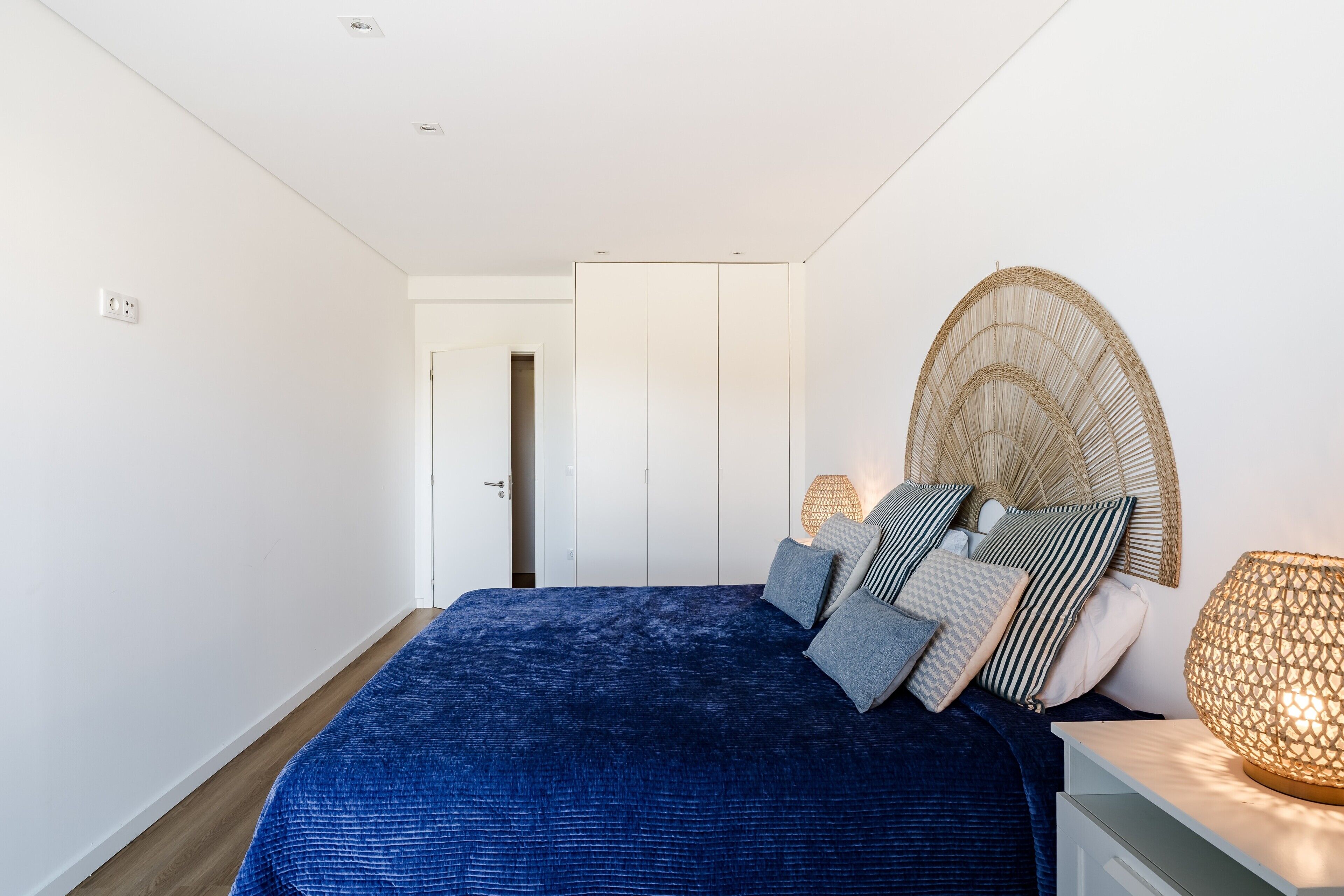 Une chambre à coucher avec un lit, des lampes de chevet, une porte et un luminaire fixé au mur.