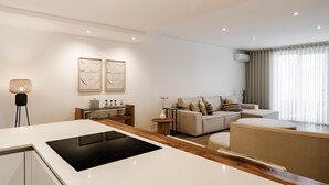 A modern living room with a sofa, a coffee table, and a kitchen area with a stove.