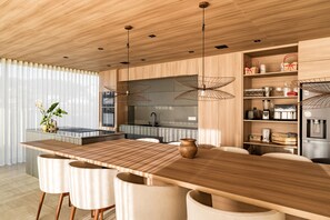 Una cocina moderna con una isla de madera, taburetes de bar, luces colgantes y un horno empotrado.