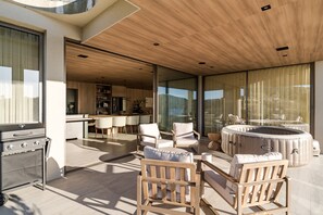 Un espacio al aire libre moderno con una parrilla, asientos y un jacuzzi.