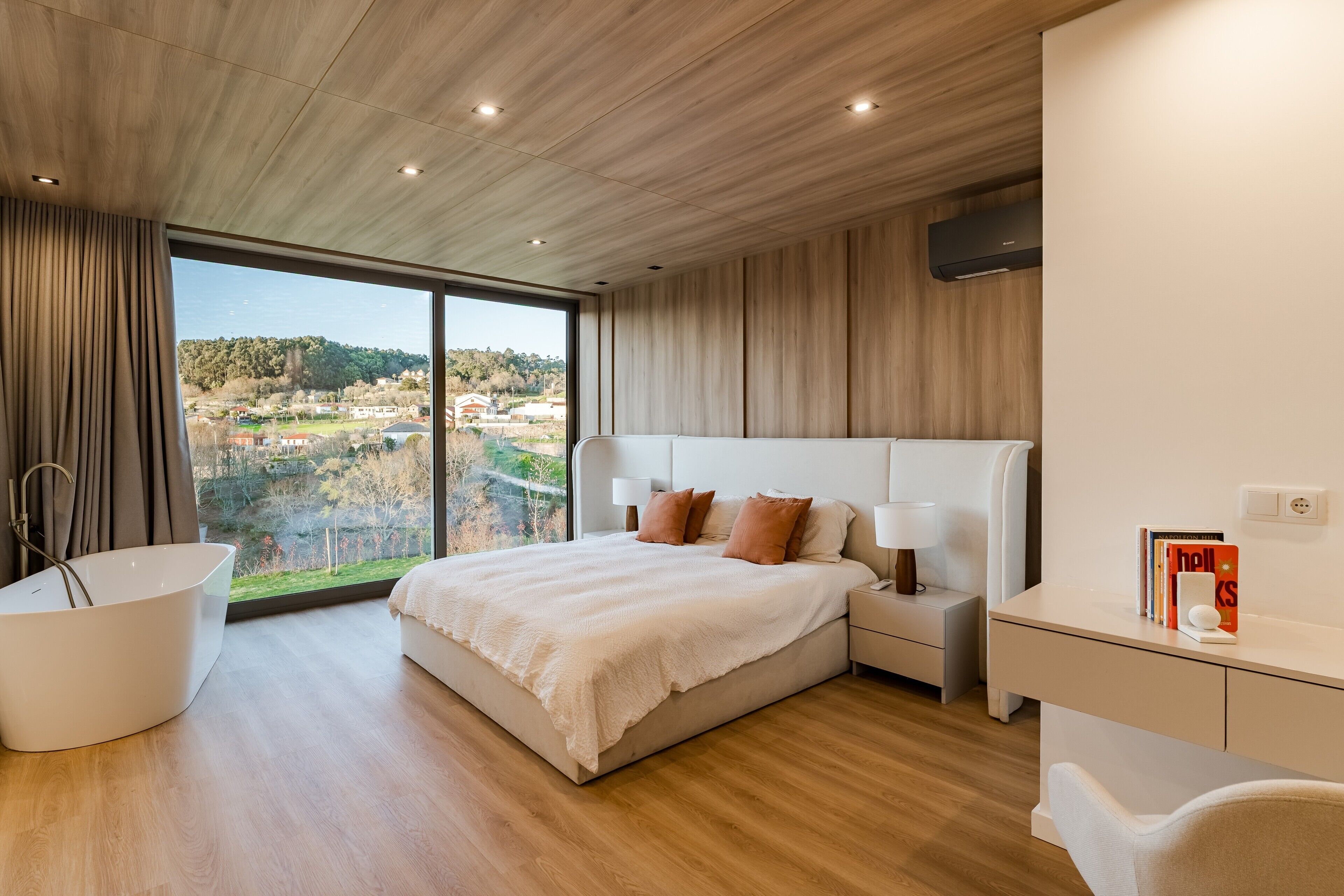 Une chambre moderne avec un grand lit, une baignoire et une vue sur la ville.