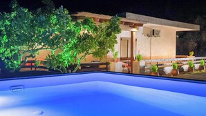 Une piscine avec un espace patio, une table à manger et des plantes en pot.