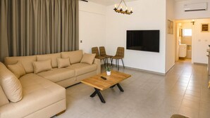 Un salon avec un canapé beige, une table basse en bois et deux fauteuils.