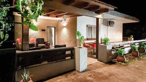 Un espace extérieur aménagé en patio, avec un coin salon couvert, une table à manger et des plantes en pot.