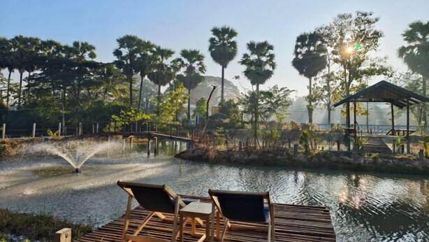 A serene outdoor area with a water feature, wooden deck with chairs, and a gazebo. - AUN-I-NA Home stay at Nakhon Phanom (Nakhon Phanom)