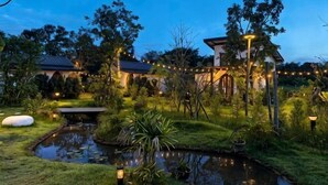A garden with a pond, string lights, and traditional architecture. - AUN-I-NA Home stay at Nakhon Phanom (Nakhon Phanom)