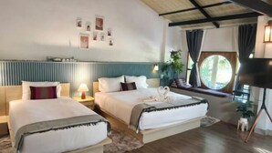 A hotel room with two beds, a large window with curtains, a TV, and a wall with framed pictures. - AUN-I-NA Home stay at Nakhon Phanom (Nakhon Phanom)