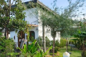 A white building with a garden in front.
