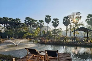 A tranquil outdoor setting with a wooden deck, lounge chairs, a water feature, and a gazebo. - AUN-I-NA Home stay at Nakhon Phanom (Nakhon Phanom)