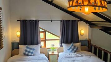 A bedroom with two beds, a ceiling fan, and a view of the outdoors.