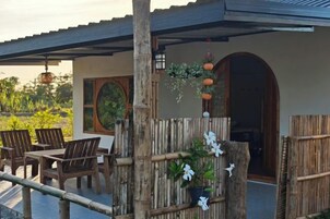 An outdoor seating area with wooden furniture and a bamboo fence.