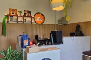 A reception area with a coffee machine, a sign reading 'HOT KHON,' and a plant. - AUN-I-NA Home stay at Nakhon Phanom (Nakhon Phanom)