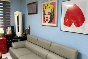 A room with a beige sofa, a red cabinet, and a framed artwork on the wall.
