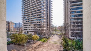 A high-rise building with multiple floors, a paved walkway, and some greenery.