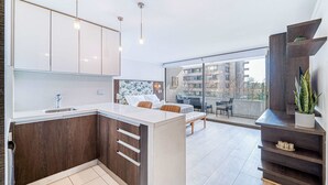 A modern kitchen with a large island, wooden cabinets, and a dining area with a view.