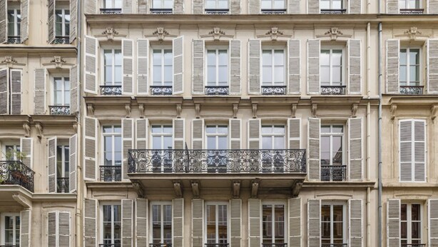 A multi-story building with uniform window shutters, balconies with wrought iron railings, and classical architectural details. - JOIVY Delightful 1Bed studio w/ shared co-working (Paris)