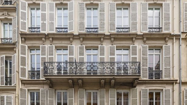 A multi-story building with uniform window shutters and ornate balcony railings.