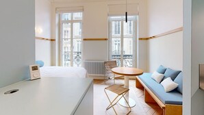 Ein Hotelzimmer mit einem Bett, einem runden Tisch, einer Couch und einem Heizkörper.