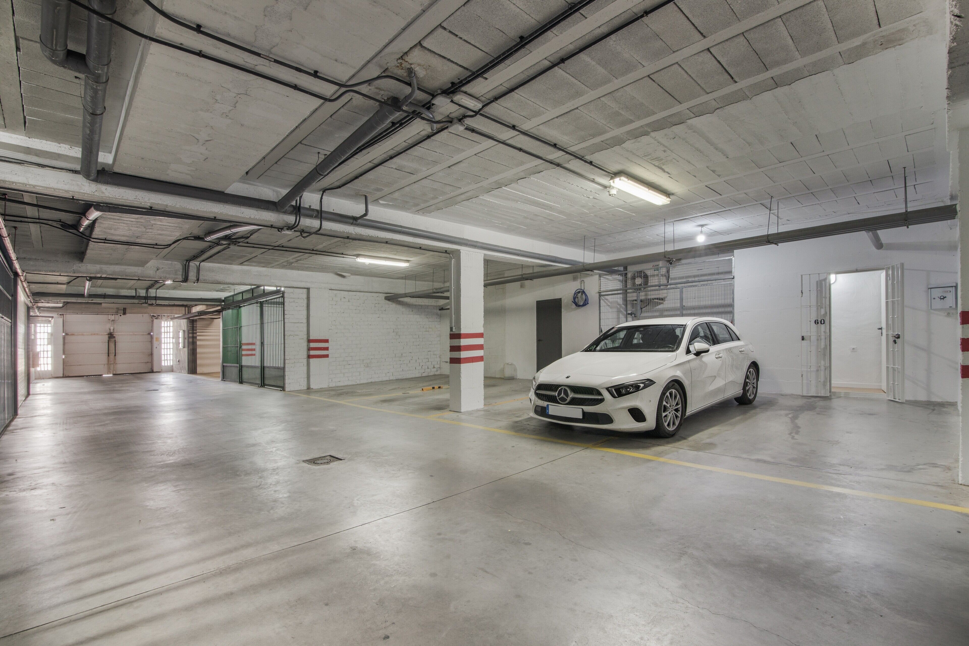 Eine Parkgarage mit einem weißen Auto in einem Stellplatz.