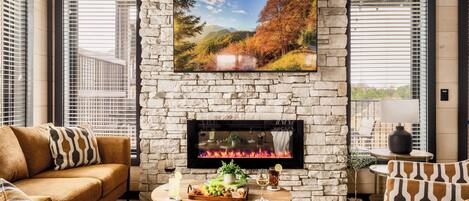 A cozy living room with a stone fireplace, a large TV mounted above it, and a comfortable sofa.