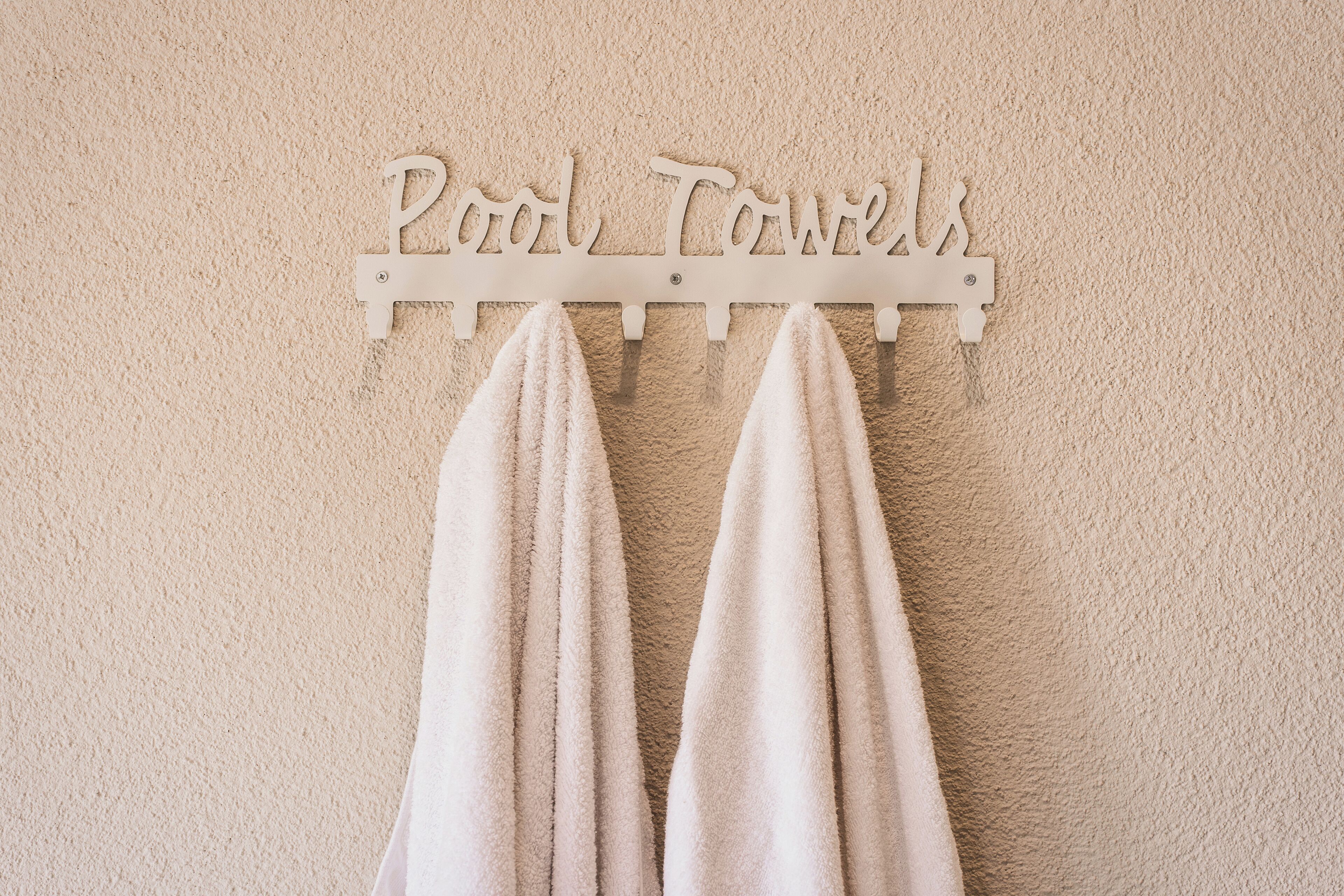 A towel rack with two towels hanging on it and the words "Pool Towels" written above.