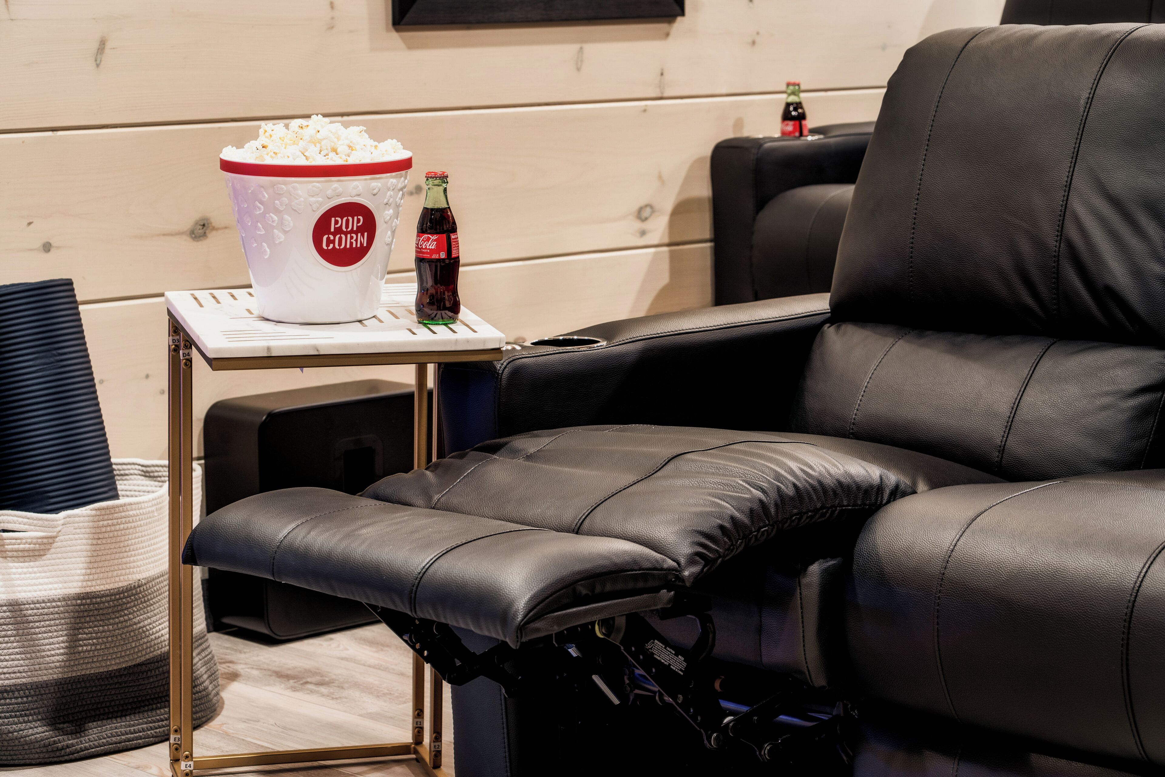 Un fauteuil inclinable, avec un bol de pop-corn et une bouteille de Coca-Cola posés sur une petite table.