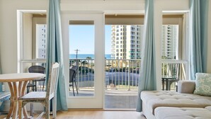 A room with a balcony, a dining table, and a sofa.